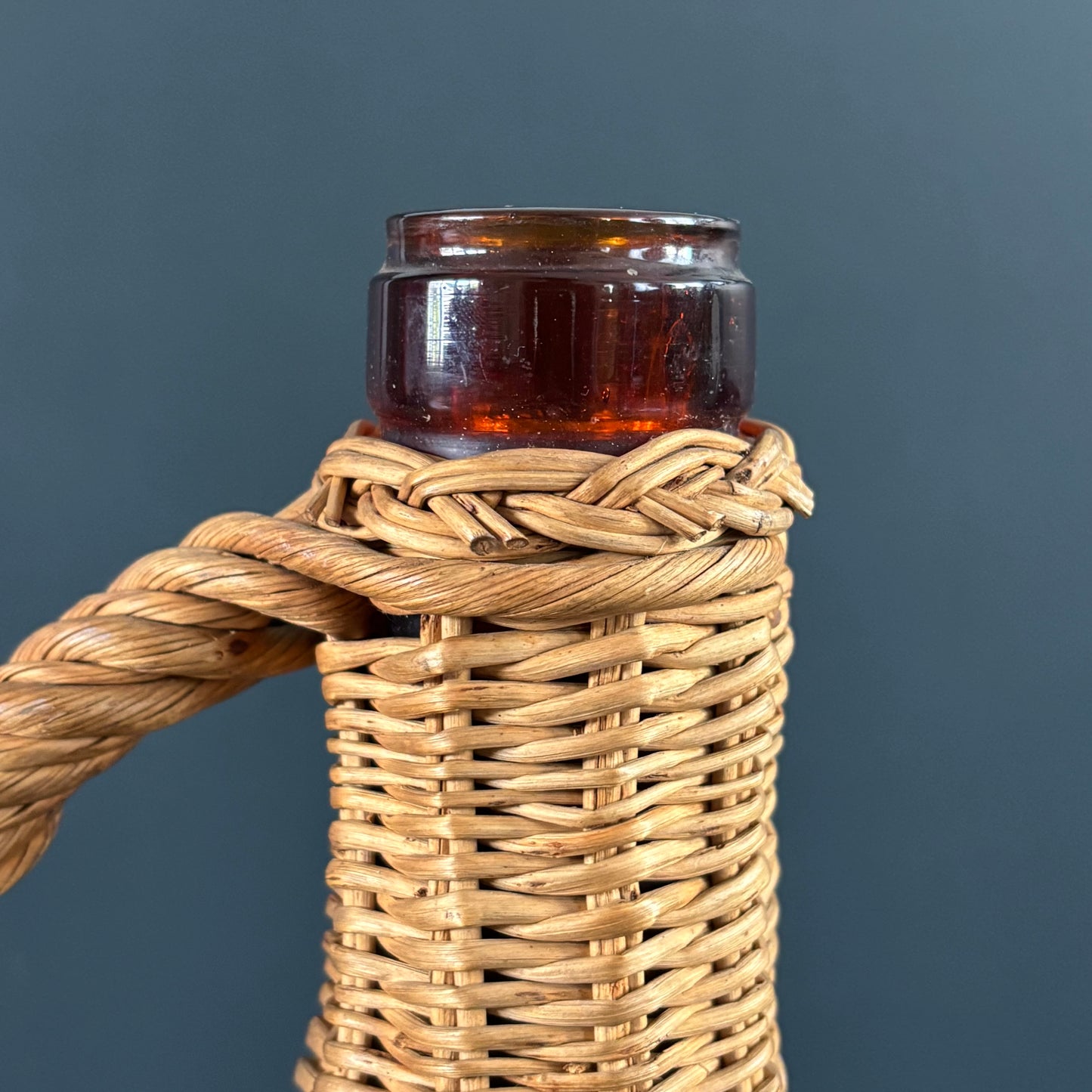 Bouteille en verre ambré dans son panier à poignée en osier - Ref 1232