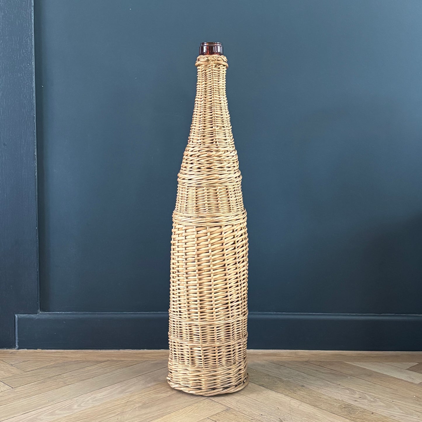 Bouteille en verre ambré dans son panier à poignée en osier - Ref 1232