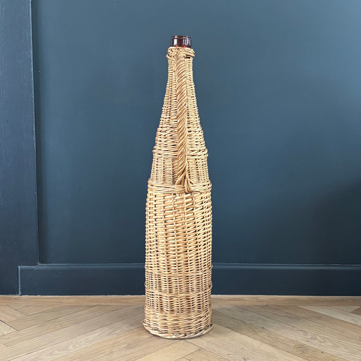 Bouteille en verre ambré dans son panier à poignée en osier - Ref 1232