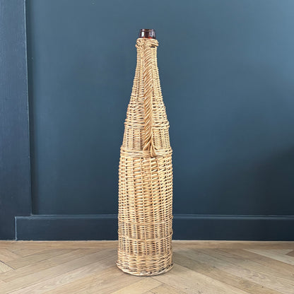 Bouteille en verre ambré dans son panier à poignée en osier - Ref 1232