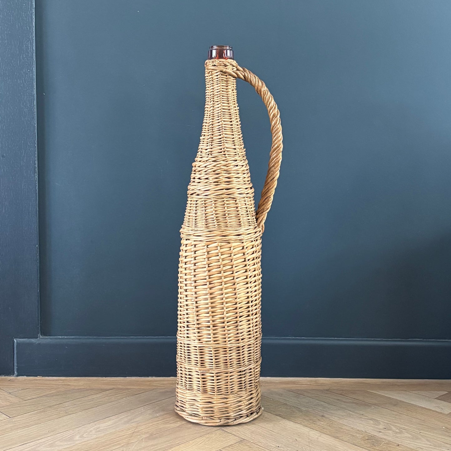 Bouteille en verre ambré dans son panier à poignée en osier - Ref 1232