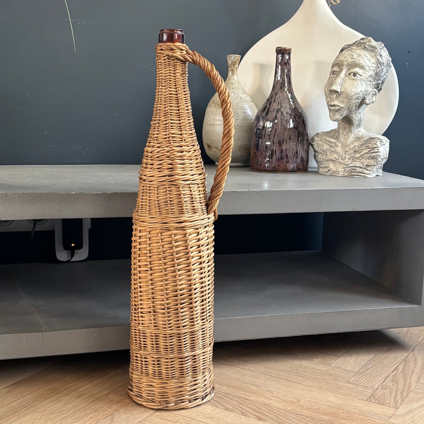 Bouteille en verre ambré dans son panier à poignée en osier - Ref 1232