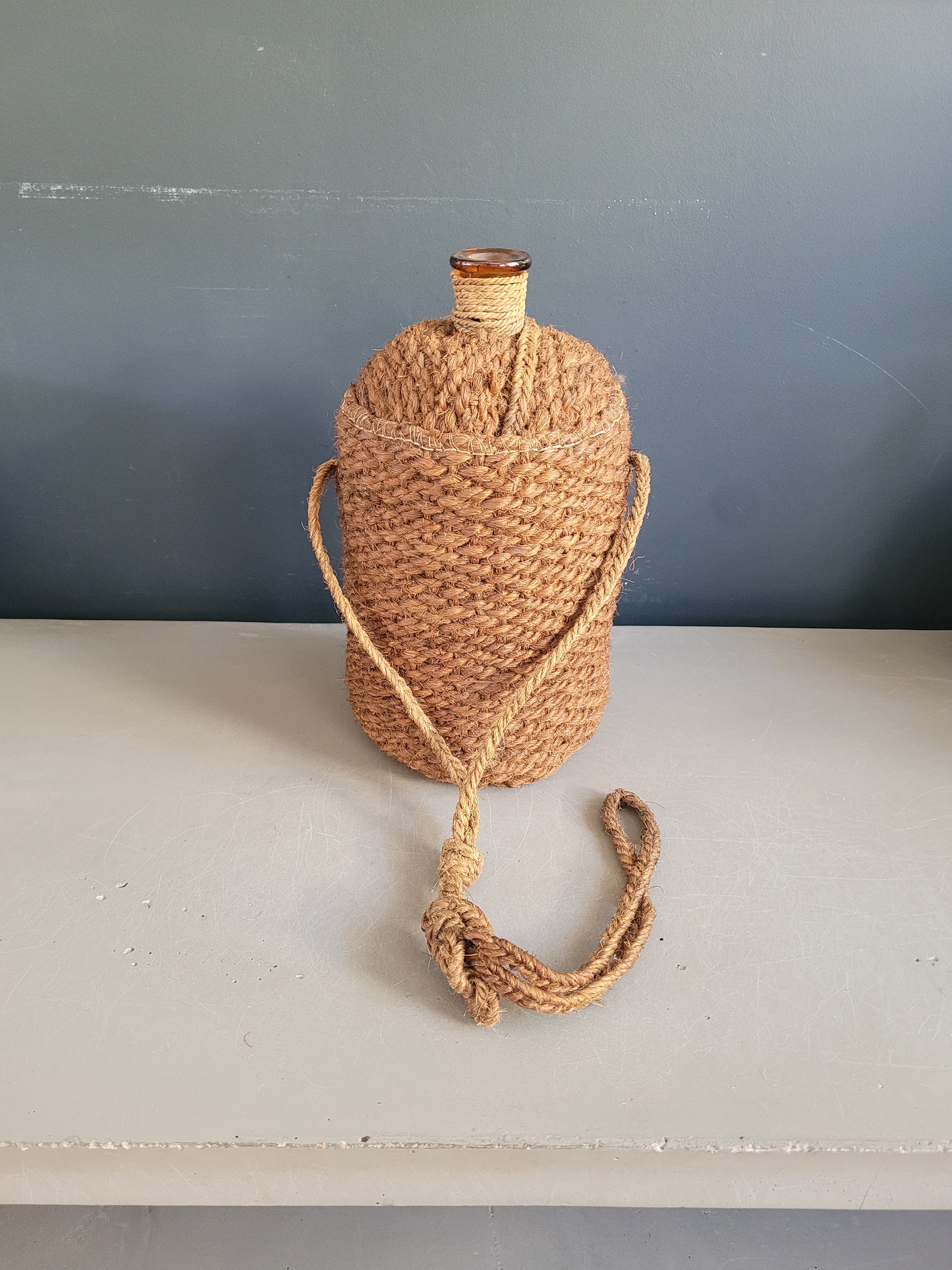 Bouteille ancienne en verre ambré et sac de transport en chanvre - Ref 657